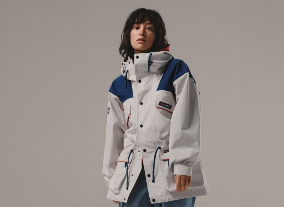 A woman stood up facing the camera wearing a white Berghaus Trango jacket with blue shoulders